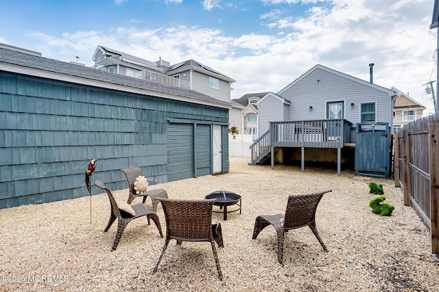 back of property with a fire pit, an outbuilding, a deck, a fenced backyard, and a storage unit
