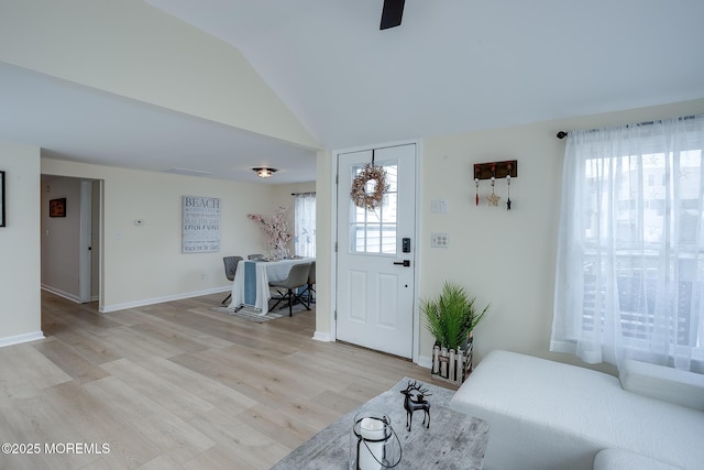 entryway featuring light wood-style flooring, baseboards, vaulted ceiling, and a wealth of natural light