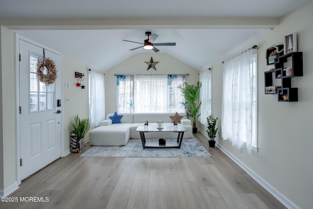 unfurnished living room with light wood-type flooring, vaulted ceiling with beams, a healthy amount of sunlight, and ceiling fan