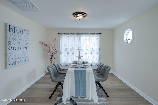 dining area with baseboards, visible vents, and wood finished floors