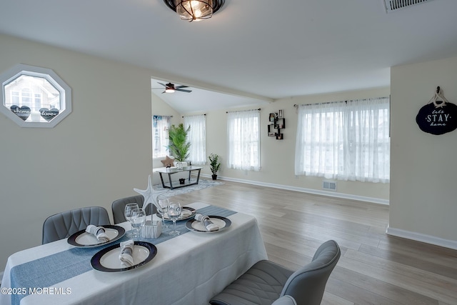 dining room with ceiling fan, visible vents, vaulted ceiling, and wood finished floors