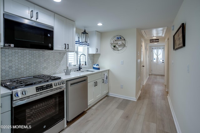 kitchen with white cabinetry, light countertops, a sink, and stainless steel appliances