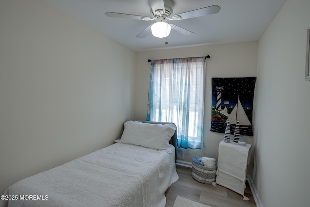 bedroom featuring ceiling fan, multiple windows, and light wood finished floors