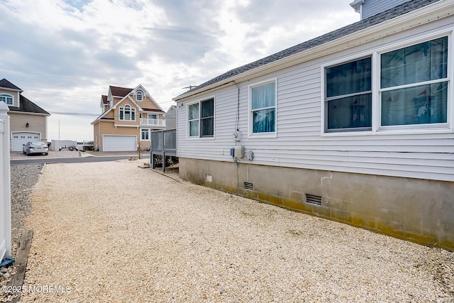 view of side of property with crawl space and a shingled roof