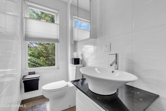 bathroom with toilet, vanity, and tile walls
