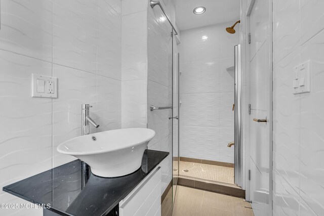 bathroom featuring a shower stall, vanity, tile walls, and tile patterned flooring