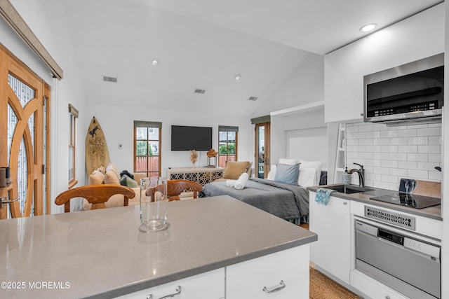 kitchen featuring white cabinets, a sink, black electric stovetop, and backsplash