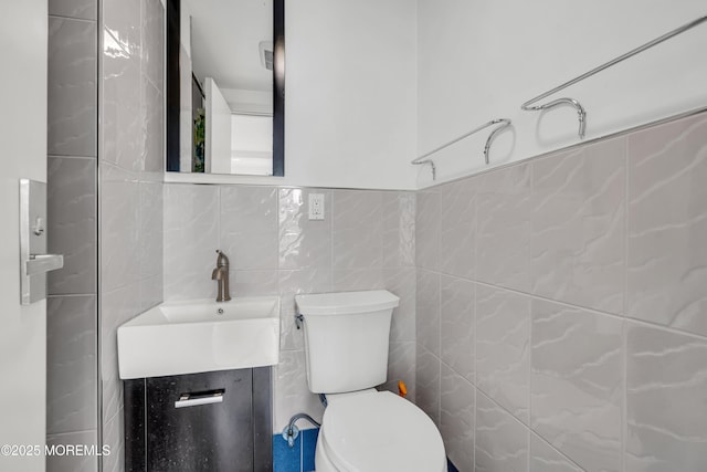 half bathroom with tile walls, toilet, and vanity