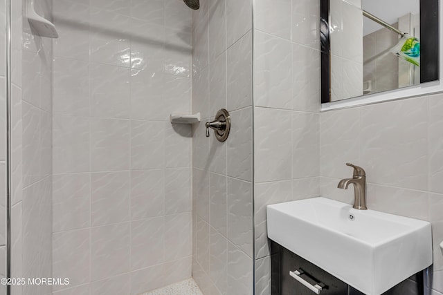 bathroom featuring tile walls, a tile shower, vanity, and tasteful backsplash