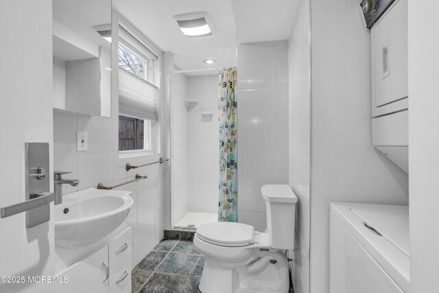 full bath with stacked washer and clothes dryer, vanity, tile walls, toilet, and a shower stall