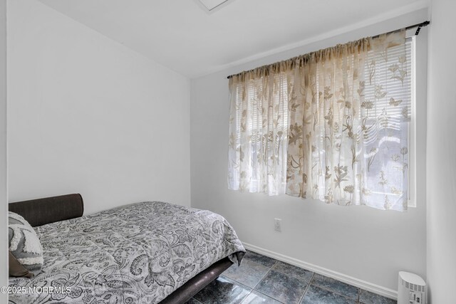 bedroom featuring baseboards and stone finish flooring