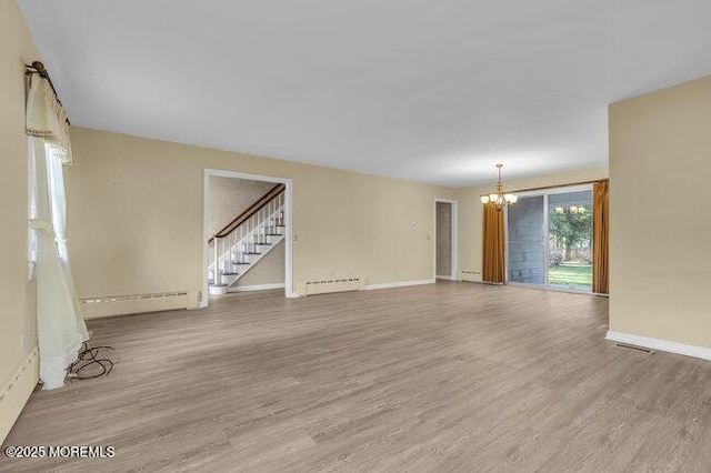 unfurnished living room with stairs, an inviting chandelier, baseboard heating, a baseboard radiator, and wood finished floors