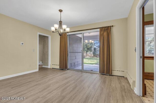 unfurnished room featuring a wealth of natural light, light wood-style floors, and a chandelier
