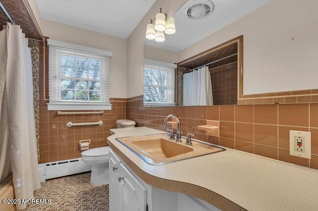 bathroom featuring tile walls, visible vents, toilet, vanity, and a baseboard heating unit
