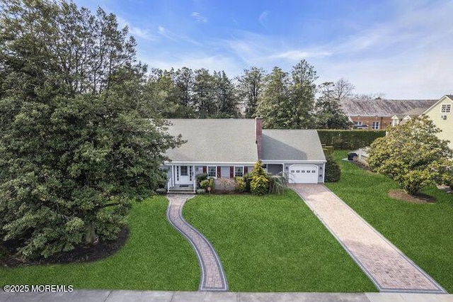 view of front facade with a chimney, driveway, a front lawn, and an attached garage
