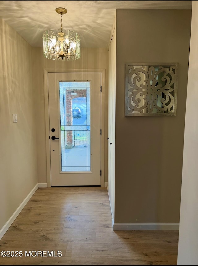 entryway with wood finished floors, a chandelier, and baseboards