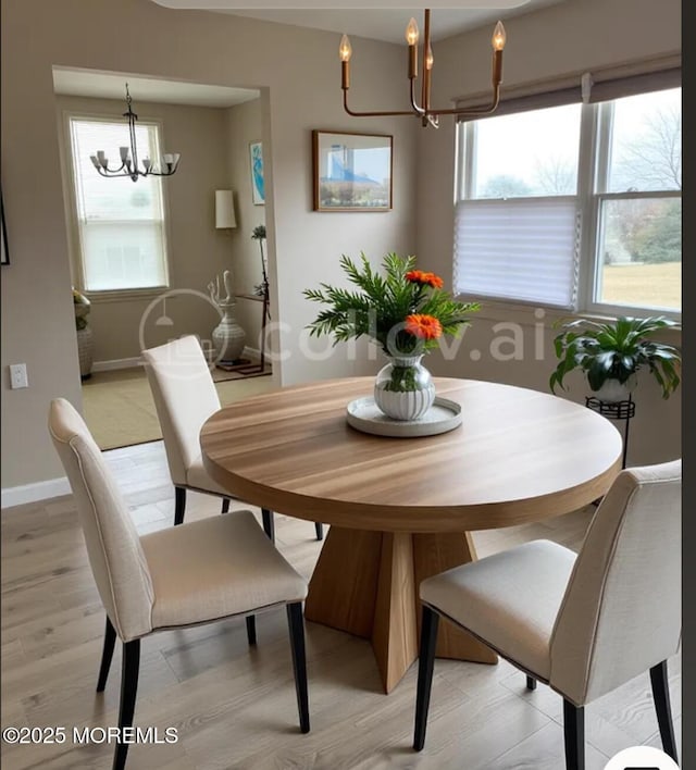 dining room featuring baseboards, an inviting chandelier, and light wood finished floors