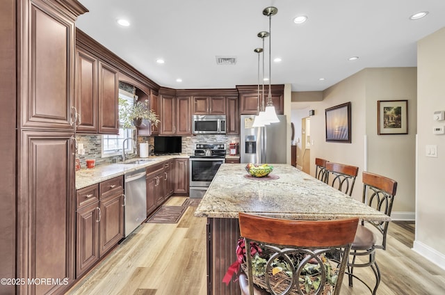 1792 Buttonwood Ave, Toms River, NJ 08755 - kitchen with visible vents, appliances with stainless steel finishes, a sink, light wood finished floors, and a breakfast bar area