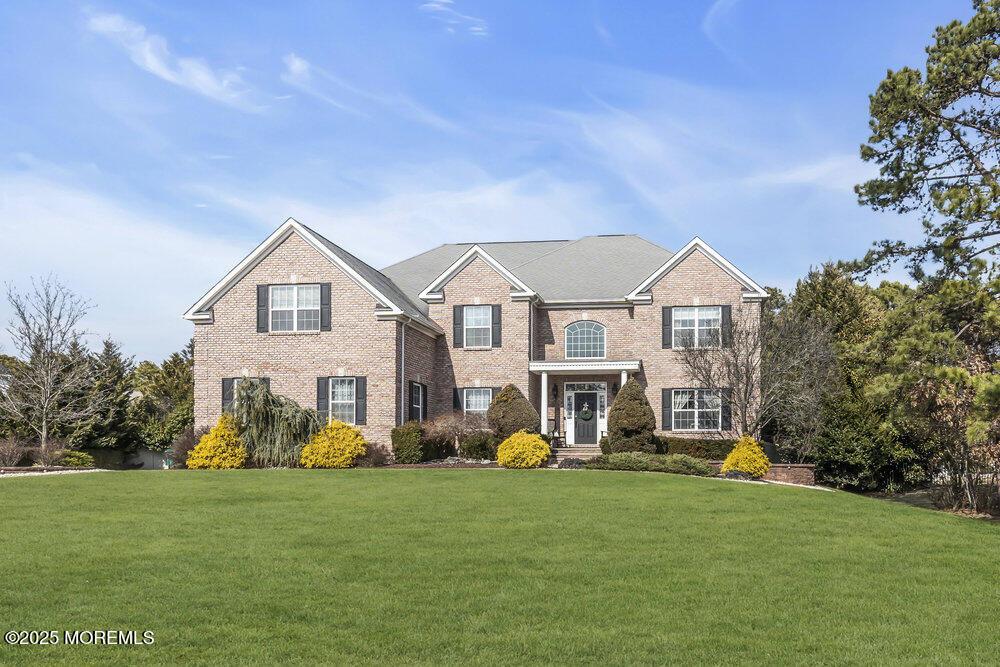 colonial house with brick siding and a front yard