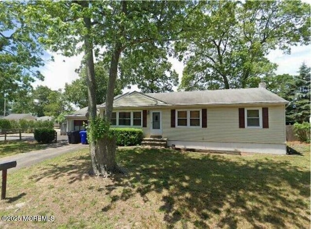 ranch-style home with an attached garage, a chimney, fence, aphalt driveway, and a front lawn