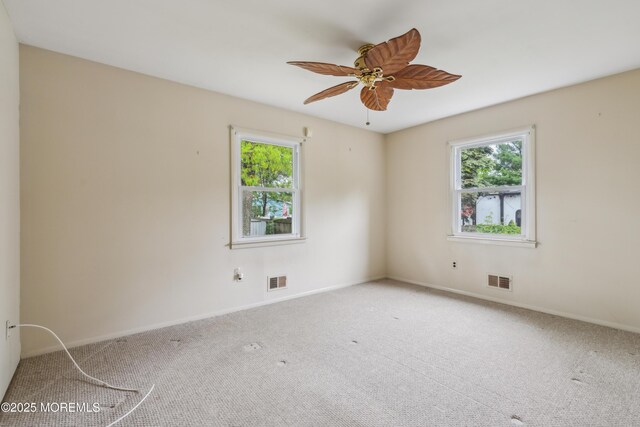 spare room featuring healthy amount of natural light, carpet, baseboards, and ceiling fan
