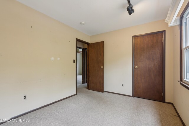 unfurnished bedroom featuring light carpet and baseboards