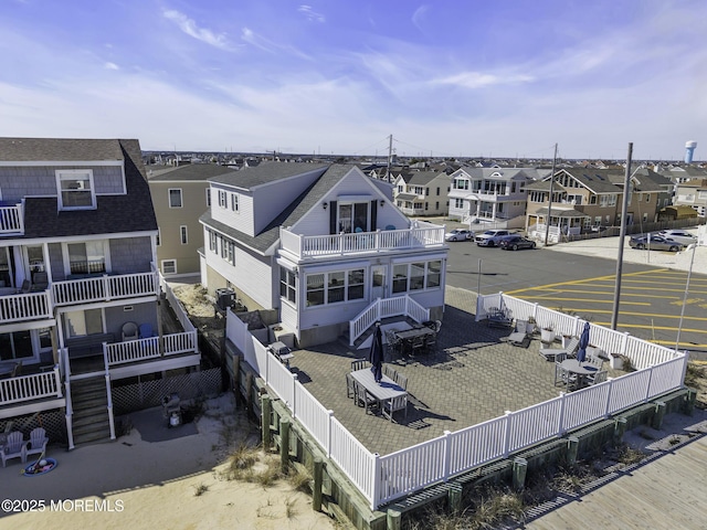 rear view of property with a balcony, a residential view, a fenced backyard, stairs, and roof with shingles