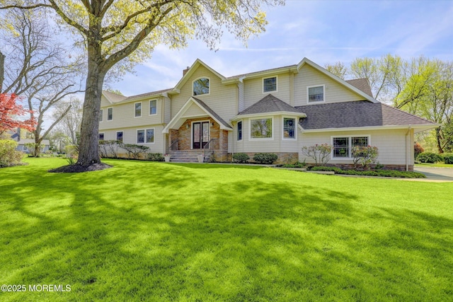 craftsman-style house featuring roof with shingles and a front yard