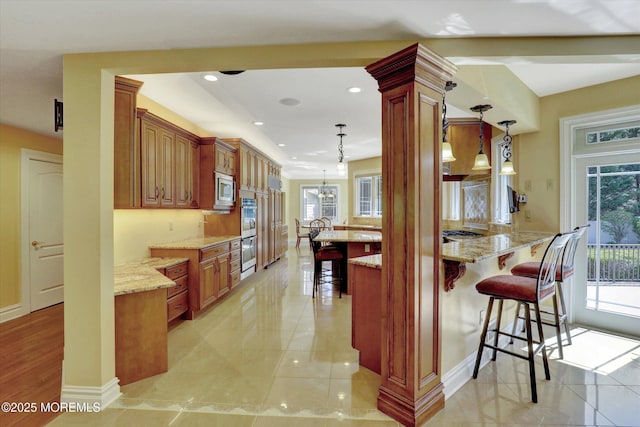 kitchen featuring a wealth of natural light, appliances with stainless steel finishes, a kitchen breakfast bar, and light stone counters