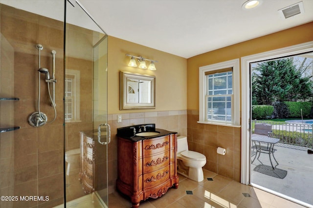 bathroom with tile patterned floors, visible vents, toilet, tile walls, and a stall shower