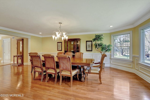 dining space with recessed lighting, a wainscoted wall, an inviting chandelier, light wood-style floors, and crown molding