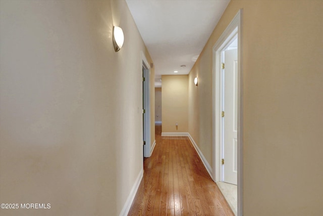 hallway featuring baseboards and light wood finished floors