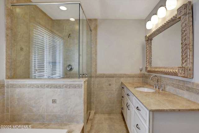 full bathroom with a shower stall, vanity, tile patterned flooring, and tile walls