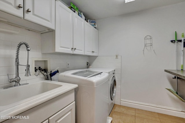 laundry area with a sink, washer and clothes dryer, tile walls, cabinet space, and light tile patterned floors