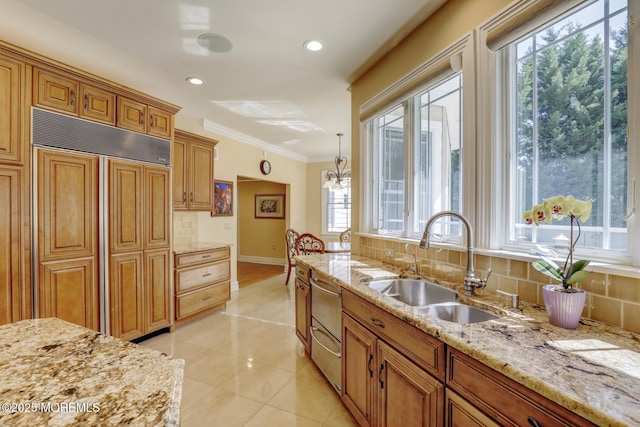 kitchen featuring a wealth of natural light, a sink, backsplash, and paneled built in refrigerator