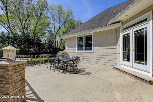 view of patio with fence, outdoor dining area, and french doors