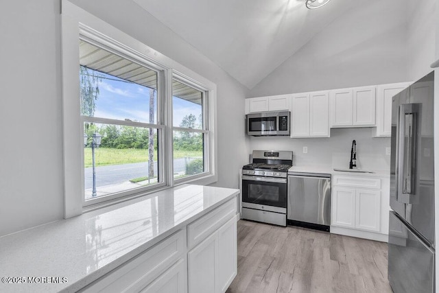 703 Stone Rd, Union Beach, NJ 07735 - kitchen featuring stainless steel appliances, a sink, vaulted ceiling, white cabinetry, and light wood finished floors
