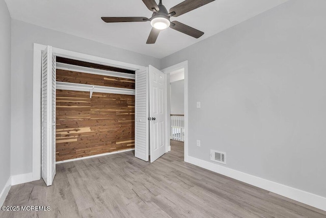 703 Stone Rd, Union Beach, NJ 07735 - unfurnished bedroom featuring wooden walls, baseboards, wood finished floors, a closet, and a ceiling fan