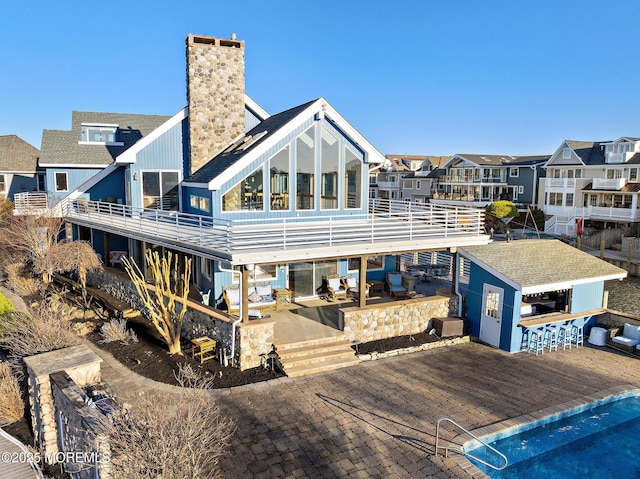 back of house with a chimney, outdoor dry bar, a residential view, and a patio area