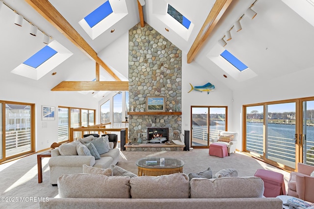 carpeted living area featuring a water view, a fireplace, beam ceiling, and a skylight