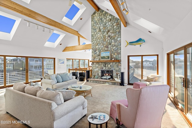 living area featuring high vaulted ceiling, a skylight, a stone fireplace, beam ceiling, and carpet floors