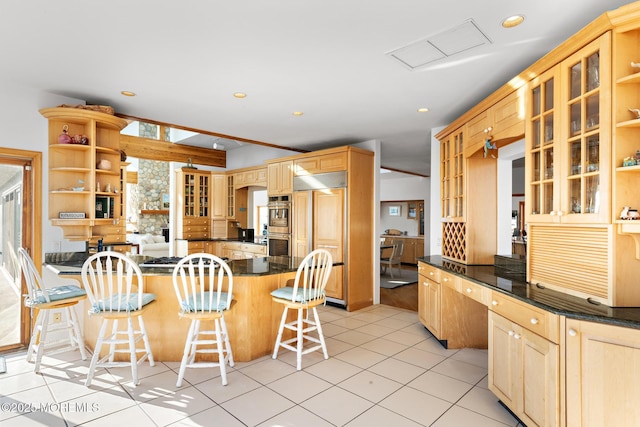 kitchen with paneled refrigerator, open shelves, a breakfast bar, glass insert cabinets, and light tile patterned floors