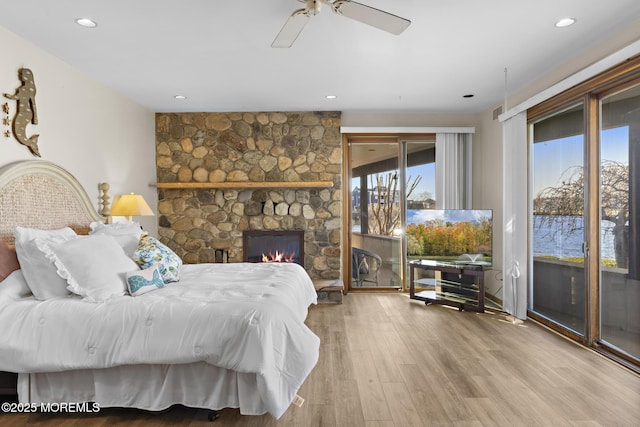 bedroom with access to exterior, wood finished floors, recessed lighting, and a fireplace