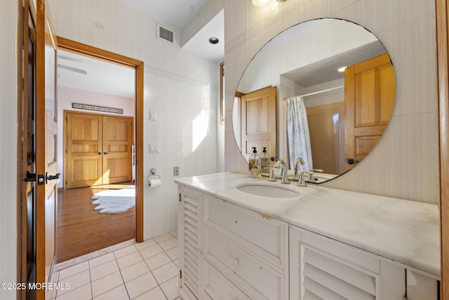 full bath with vanity, a shower with curtain, tile patterned flooring, visible vents, and tile walls