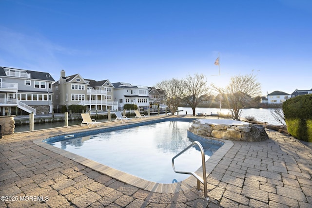 pool featuring a water view, a patio area, and a residential view