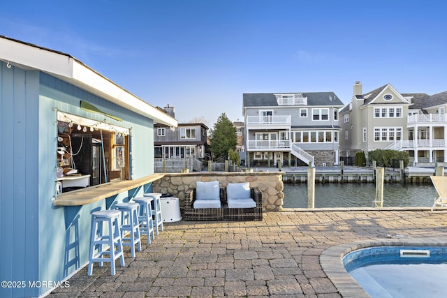 view of patio / terrace featuring a residential view, outdoor dry bar, and a water view