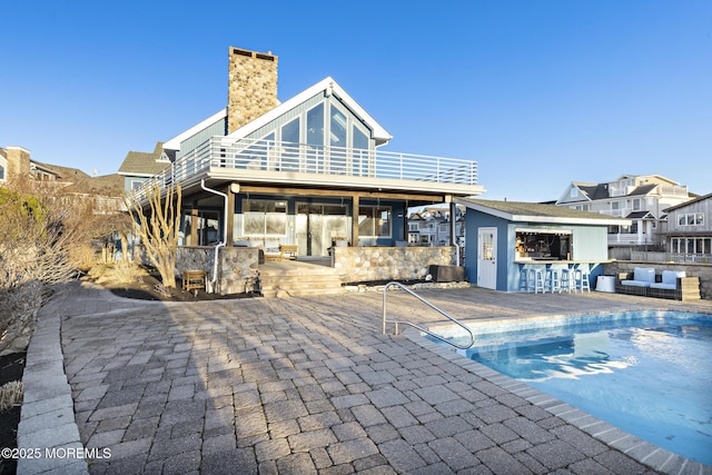 back of property featuring an outdoor living space, a chimney, a balcony, a patio, and outdoor dry bar