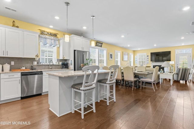 kitchen with a breakfast bar, a center island, visible vents, dark wood finished floors, and appliances with stainless steel finishes