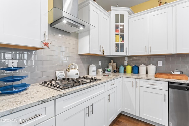 kitchen featuring appliances with stainless steel finishes, wall chimney exhaust hood, and white cabinets