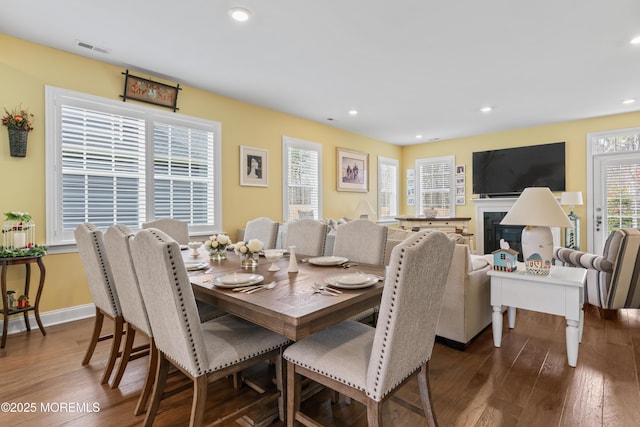 dining room featuring a fireplace, recessed lighting, dark wood-type flooring, and visible vents